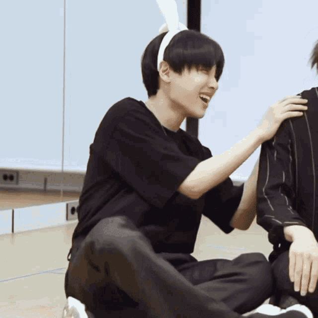 a boy wearing bunny ears is sitting on the floor with another boy
