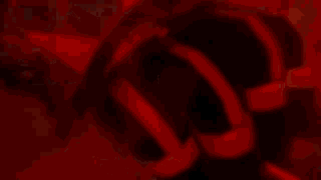 a close up of a person holding a sword in a dark room with a red background .