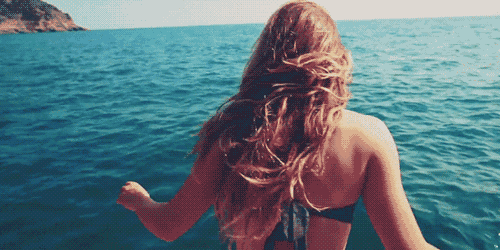 a woman in a black bikini is walking in the ocean