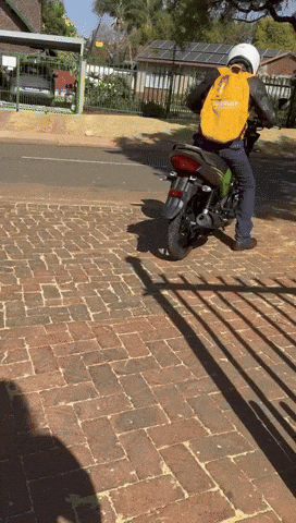 a person riding a motorcycle with a yellow backpack that says ' triumph ' on it