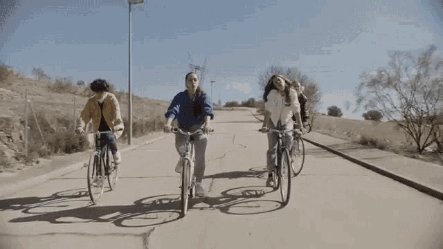 a group of young women are riding bicycles down a road .