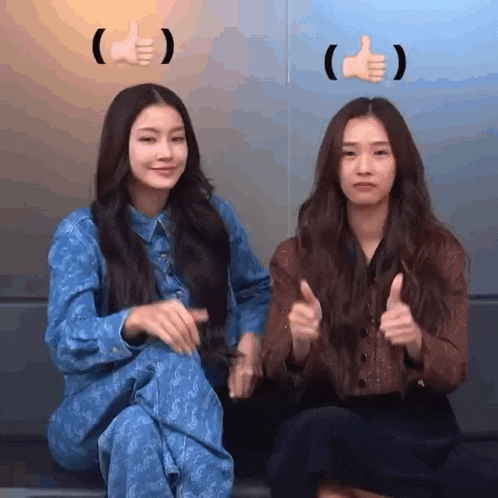 two young women are sitting next to each other and giving a thumbs up .