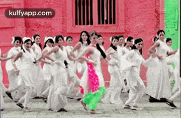 a woman in a pink dress is dancing in front of a group of women in white dresses .
