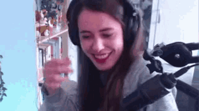 a woman wearing headphones is smiling in front of a microphone in a room .