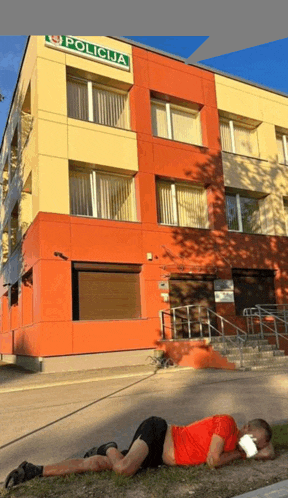 a man is laying on the ground in front of a building with the word policija on it