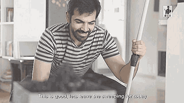 a man in a striped shirt is sweeping the floor with a mop and smiling .