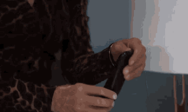 a woman in a leopard print shirt is holding a black object .