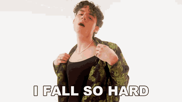 a man with curly hair is wearing a green shirt and a black tank top and says i fall so hard