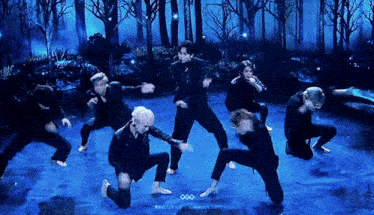 a group of people are dancing on a stage with a blue background