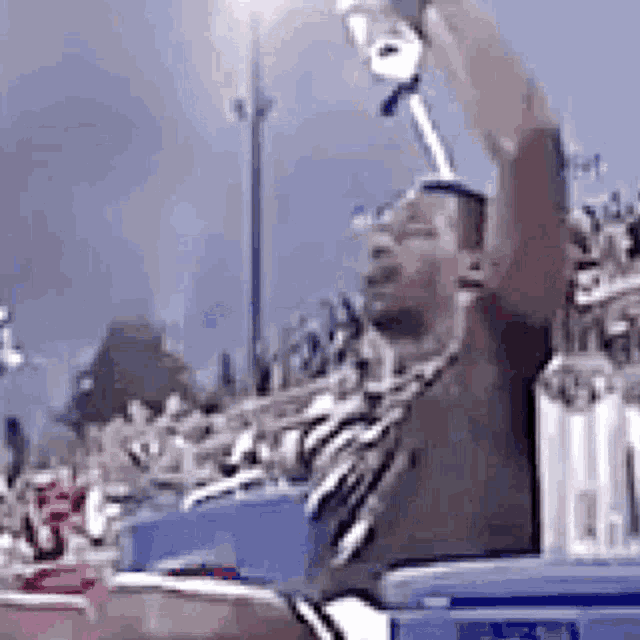 a man is holding a trophy in his hand in front of a crowd at a football game .