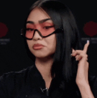 a woman wearing red sunglasses and a black jacket is making a face .