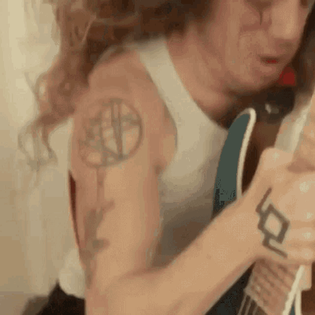 a man with a tattoo on his arm is playing a guitar