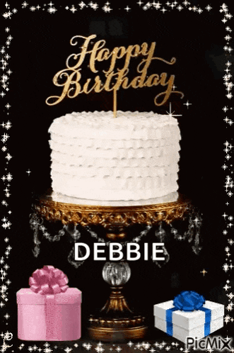 a birthday cake on a cake stand with a happy birthday topper and gifts .