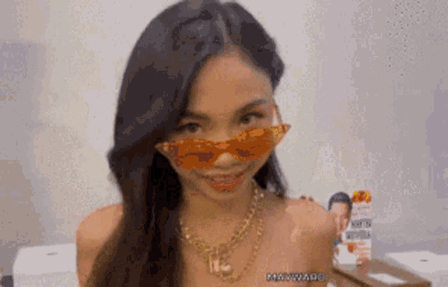 a woman wearing sunglasses and a necklace is making a face .