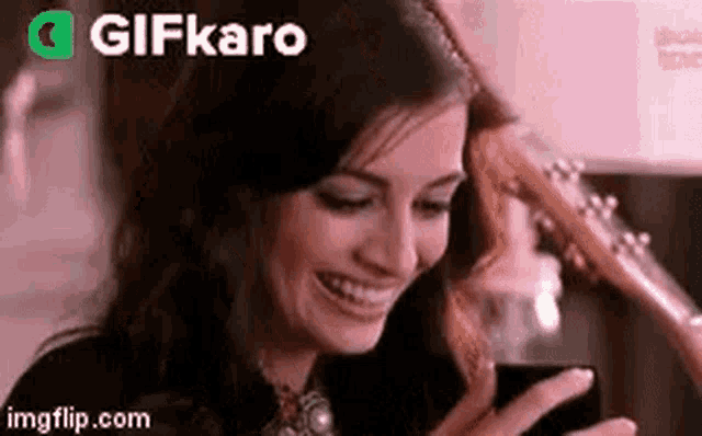 a woman is laughing while looking at her cell phone .