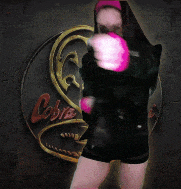 a woman is standing in front of a broken glass with the word cobra on it