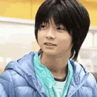 a young boy with short hair is wearing a blue jacket and a green scarf .