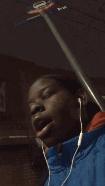 a person wearing ear buds and a blue jacket holds a basketball hoop in their hand