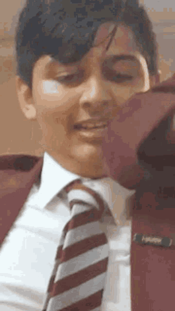 a young man in a suit and tie is smiling while adjusting his tie .