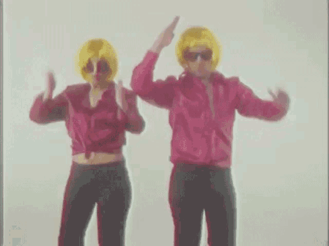 a man and a woman are dancing together while wearing yellow wigs .