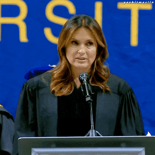 a woman in a graduation cap and gown is giving a speech in front of a sign that says " rst "