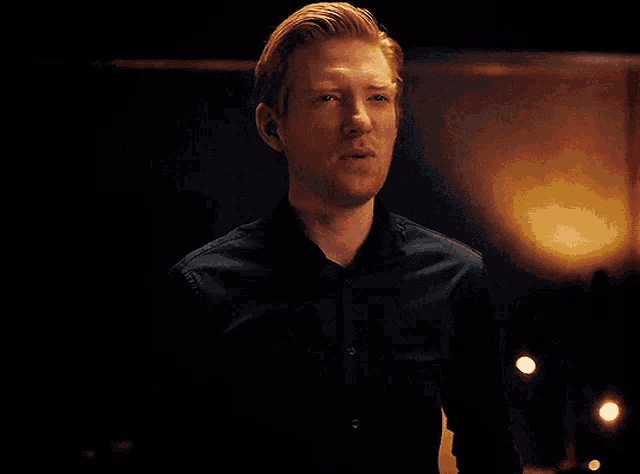 a man in a black shirt is smiling and looking at the camera