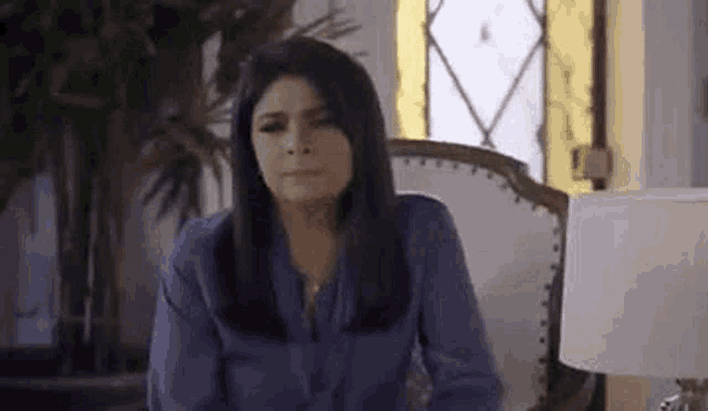a woman is sitting in a chair with a lamp in front of her .