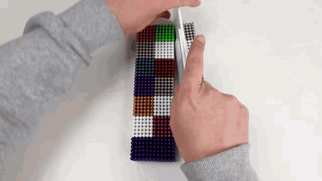 a person is playing with a cube made of magnet beads