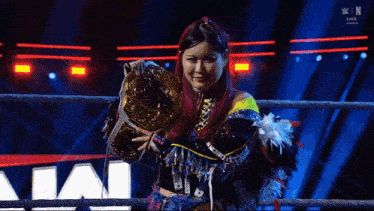 a woman in a wrestling ring is holding a championship belt