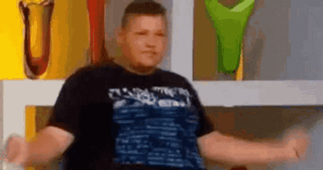 a man in a black shirt is dancing in front of a shelf with vases on it .