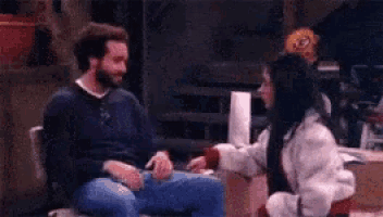 a man and a woman are sitting next to each other in a room