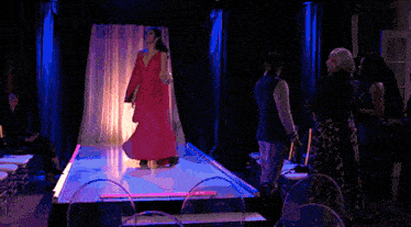 a woman in a red dress is singing into a microphone on stage