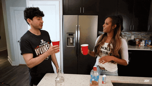 a man wearing a shirt that says ' winner ' on it is talking to a woman