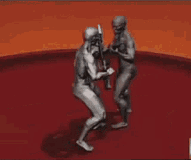 a couple of naked men are standing next to each other on a red surface .