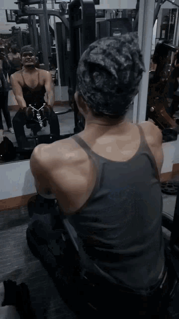 a man is kneeling down in front of a mirror in a gym lifting weights