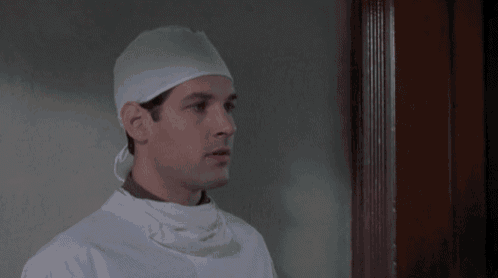 a man wearing a surgical cap and gown stands in a doorway