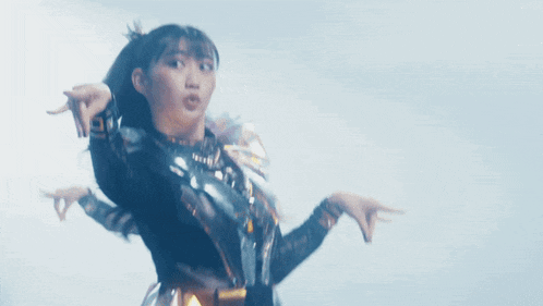 a girl in a black and gold outfit is pointing her finger