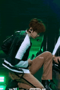 a young man is kneeling down on a stage with his pants down
