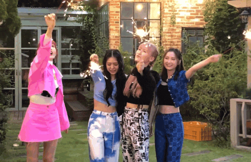 a group of young women are holding sparklers in front of a building