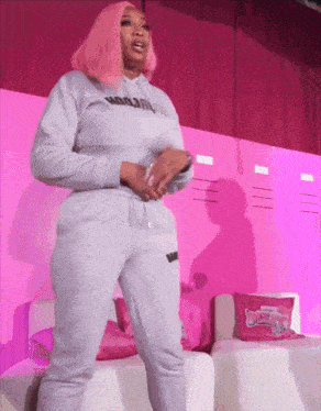 a woman with pink hair is wearing a grey hoodie that says woogirl