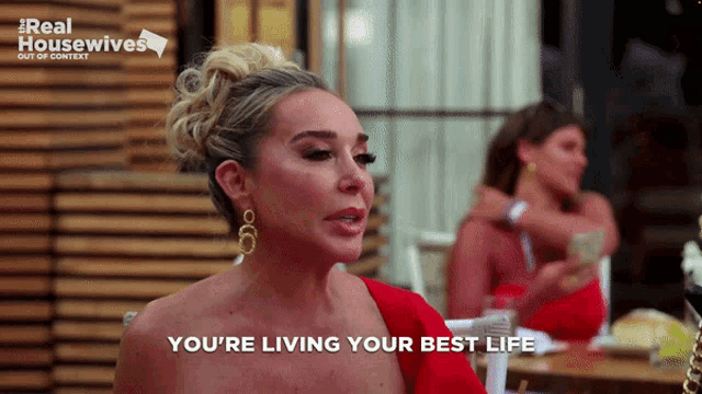 a woman in a red dress says " you 're living your best life " in front of two other women