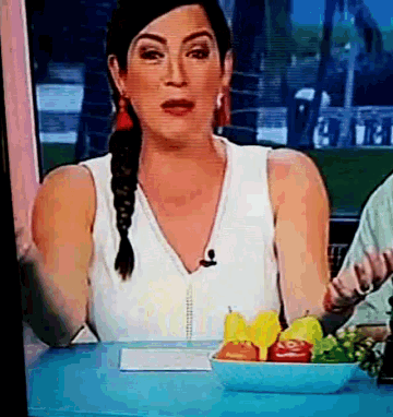a woman is sitting at a table with a bowl of fruit on it