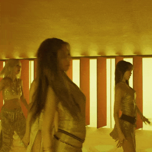 three women are dancing in a room with a yellow background