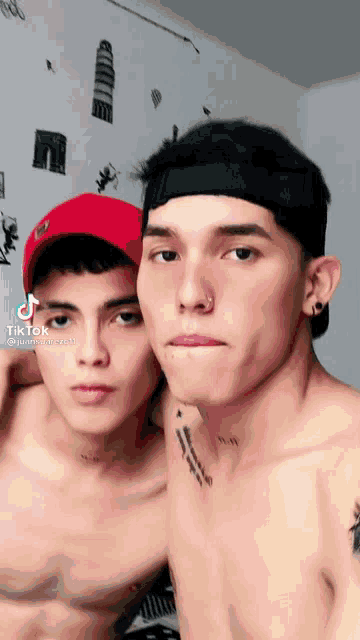 two shirtless men are standing next to each other and one has a tattoo on his chest