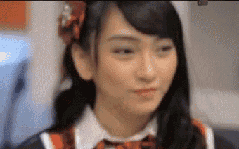 a girl in a school uniform is making a funny face and looking at the camera .