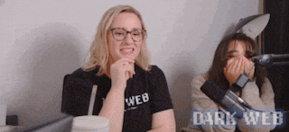 two women are laughing in front of a microphone and the words dark web are visible