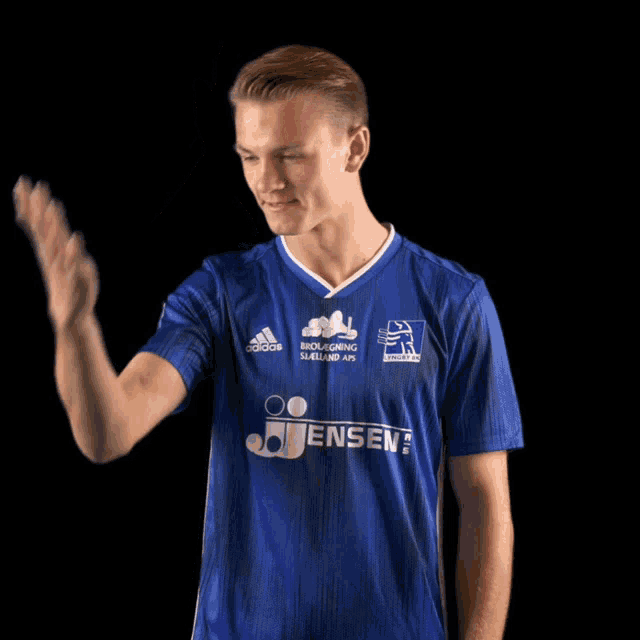 a man wearing a blue adidas shirt is waving his hand