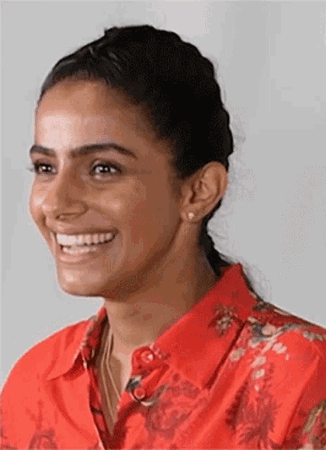 a woman wearing a red shirt and a ponytail is smiling .