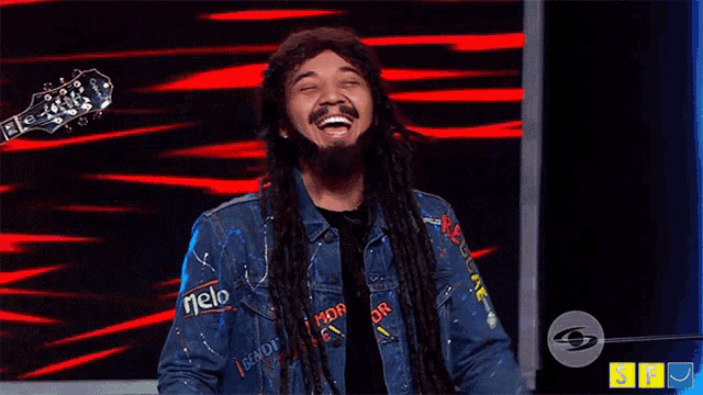 a man with dreadlocks is laughing while holding a guitar headstock