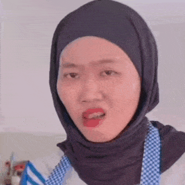 a woman wearing a hijab and an apron making a funny face .